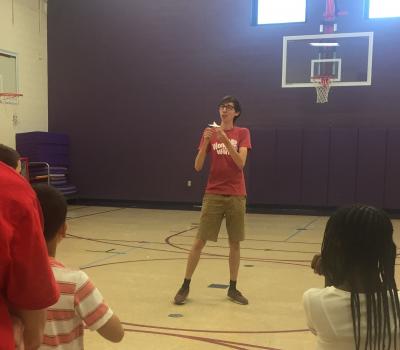 Photograph of Andrew in the gym talking to 3rd graders about aerodynamics