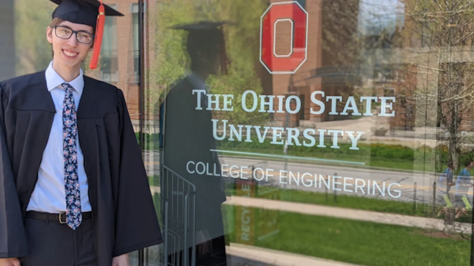 Photograph of Andrew Sabovik in front of the window at the entrance of the College of Engineering building
