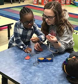 Photograph of WOW volunteer teaching a kindergartner about closed and open circuits