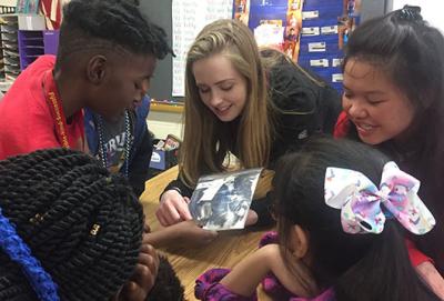 Photograph of volunteers showing elementary school children bird feathers