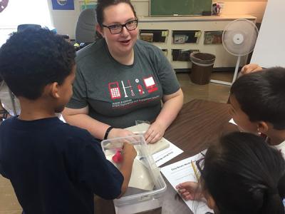Photograph of WOW student talking to 2nd graders about clay boats