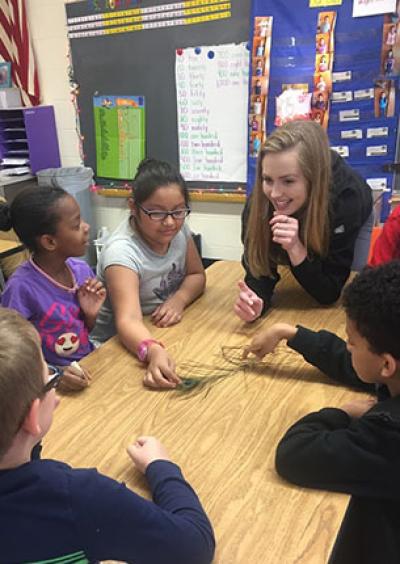 Photograph of Leah teaching 2nd graders about bird feathers