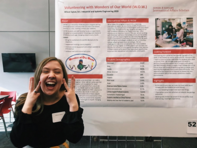 Photograph of Allison with her poster about the WOW program and showing off a WOW face too.