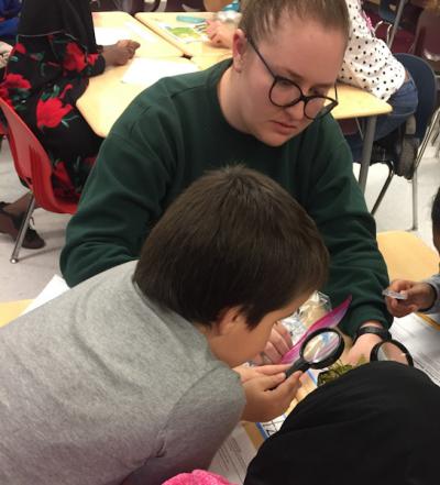 Photograph of Rebecca teaching 3rd grade students about a sundew plant from the OSU greenhouse