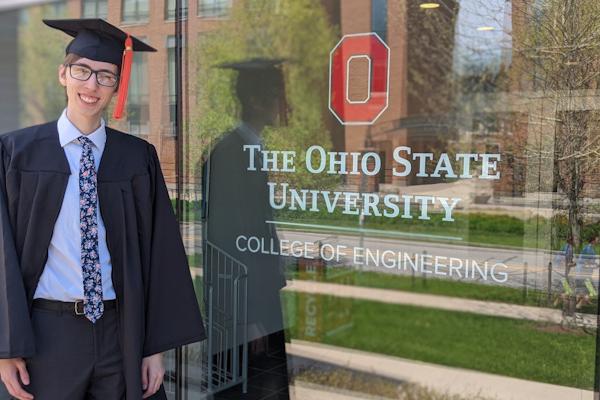 Photograph of Andrew Sabovik in front of the window at the entrance of the College of Engineering building