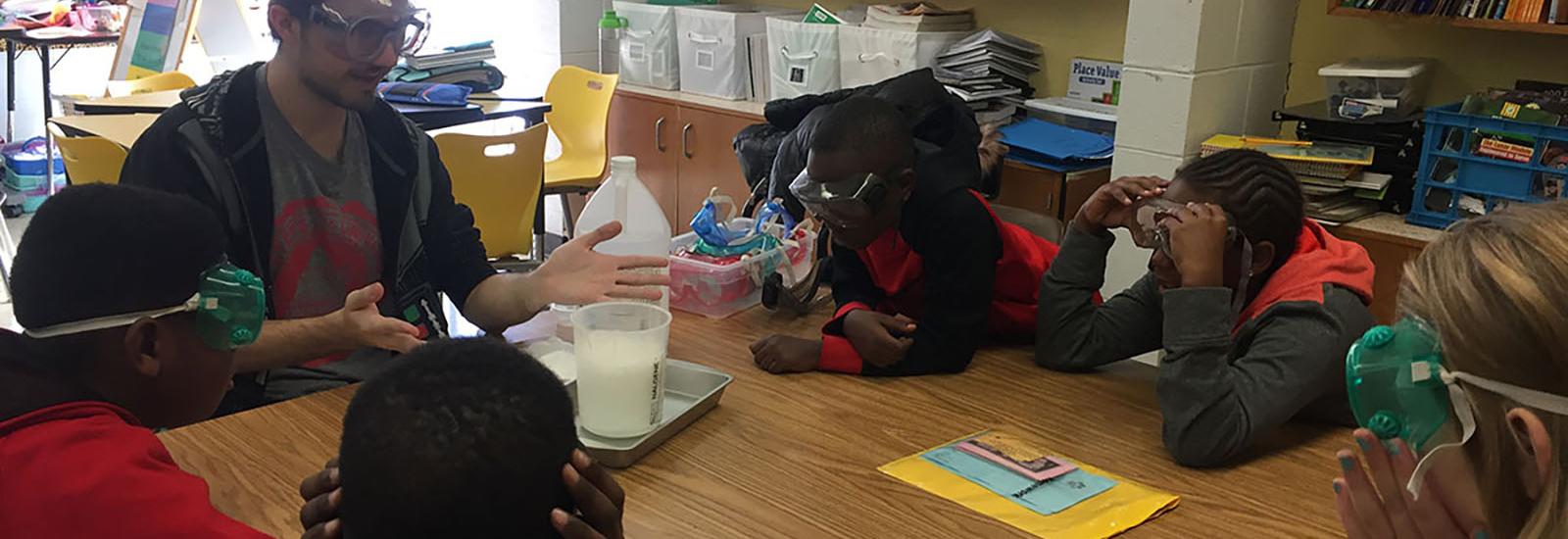 Photograph of WOW student teaching 5th graders about chemical reactions with vinegar and baking soda.